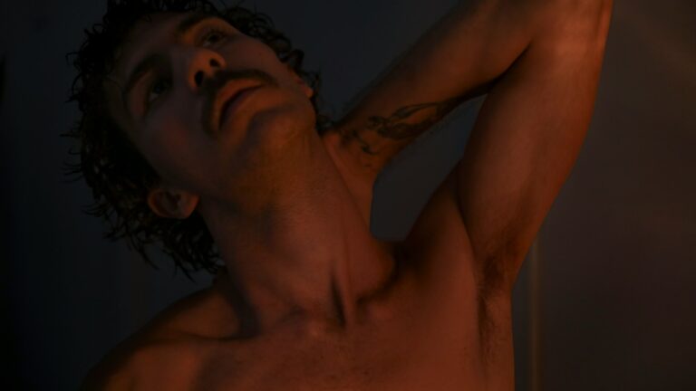 a man with no shirt on holding his arm up